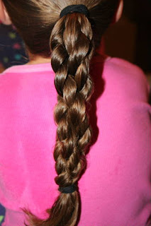 Back view of young girl's hair being styled into "Triple-Twist Ponytail' hairstyle