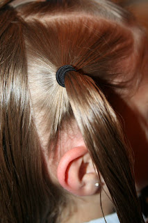 Side view of young girl's hair being styled into "Holiday Twisty Buns" hairstyle