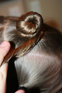 Side view of young girl's hair being styled into "Holiday Twisty Buns" hairstyle