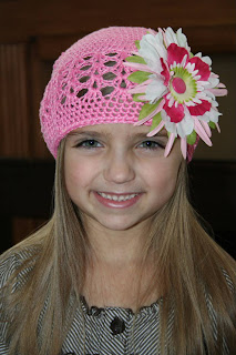 Young girl modeling a pink hat with a multi-color flower on it