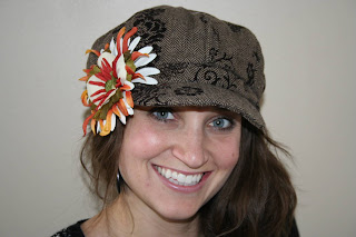 Young woman modeling a brown hat with a multi-color flower on it