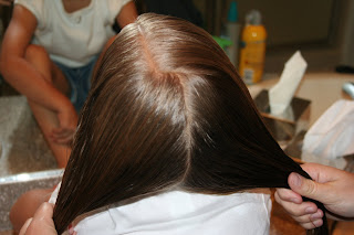 Back view of a young girl's hair being styled into “Two Hearts Twist” hairstyle