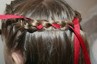 Close up of a young girl having ribbon added to her “French Designer Heart” hairstyle