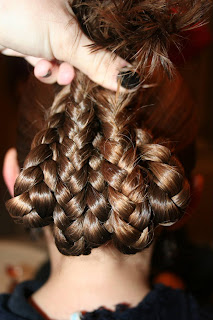 Back view of young girl's hair being styled into "bundled braids" hairstyle