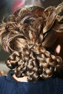 Back view of young girl's hair being styled into "bundled braids" hairstyle