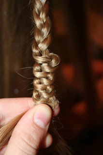 Close up view of young girl's hair being styled into "Teen Slide-Up Braid" hairstyle outside