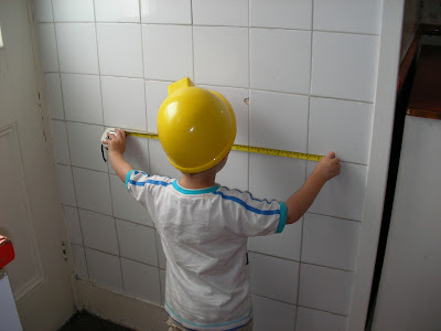 builder measuring tiles with tape measure in bob the builder hard hat