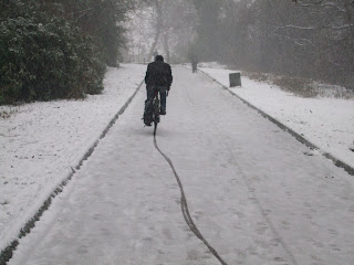 A cyclist leaves a wavy track through the snow in Heaton Park