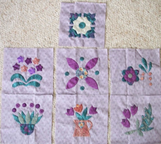 seven applique blocks of flowers and leaves in purples and greens