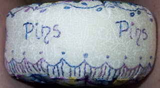 close-up of embroidery which says pins and includes flowers