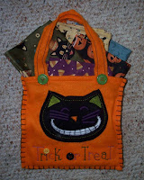 Orange felt bag with black cat on front containing five fat quarters with Halloween prints
