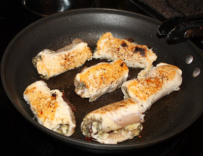 skillet with 6 pesto chicken rolls cooking, slightly browned