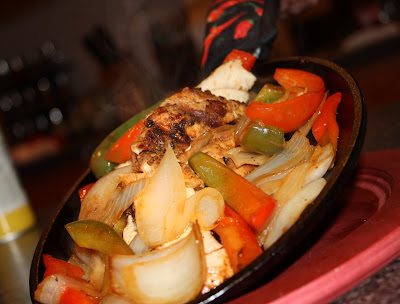 skillet with chicken, bell peppers, and onions