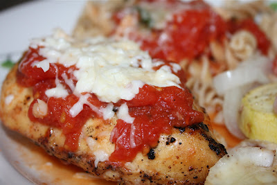 close up of piece of chicken topped with tomato sauce and cheese