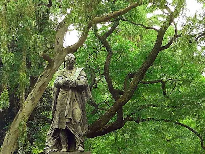 Estatua del prócer cabizbajo con los brazos cruzados