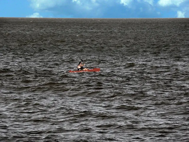 Hombre navegando en piragua en pleno mar.