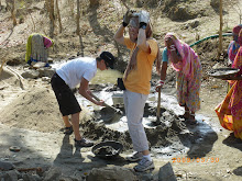 INDIA: Volunteers mixing cement and carrying it to the wall-like structure.