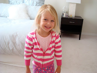 Young girl wearing pink smiling standing in bedroom