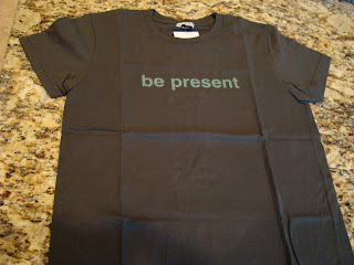 Grey t-shirt with the phrase be present 