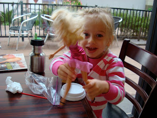 Young girl playing with barbie at coffee shop table