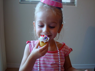 Young girl wearing birthday hate eating cupcake