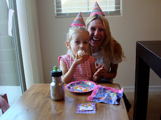 Young girl eating cupcake with woman behind her smiling