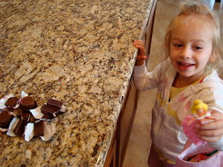 Young girl holding doll looking at candy on countertop
