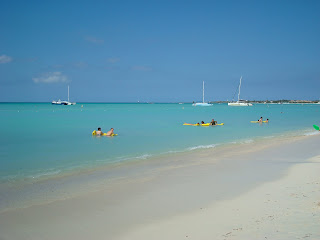 White sandy beach in Aruba with boats and people in water