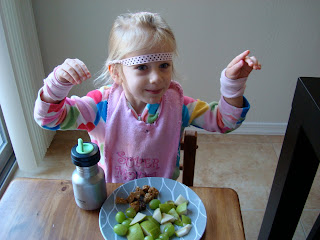 Young child showing off wristbands at table with snacks