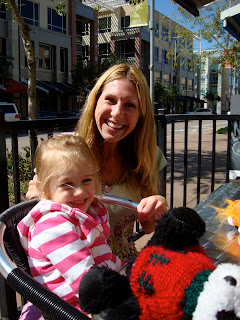 Woman smiling with young girl sitting outside of coffee shop