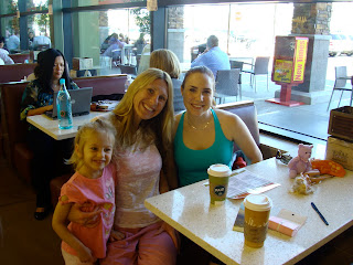 Two women in booth with young girl standing beside them