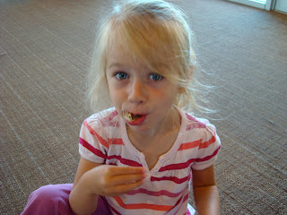 Young girl sitting on floor smiling eating a snack