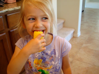 Young girl chewing on a piece of corn on the cob