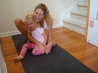 Woman and little girl sitting on yoga mat hugging and smiling