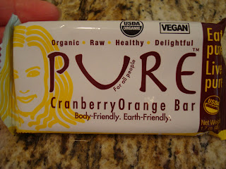 Hand holding Pure Cranberry Orange Bar in package