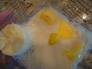 Ingredients for smoothie that contain banana, almond milk, mango and agave in blender