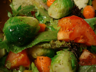 Greens topped with Brussel sprouts and tomatoes tossed in dressing