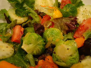 Close up of mixed greens topped with vegetables and dressing in white bowl