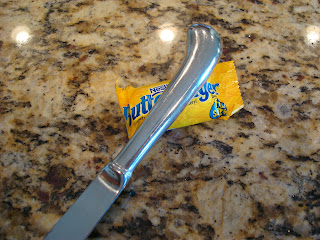 End of butter knife crushing up a mini sized butterfinger candy bar