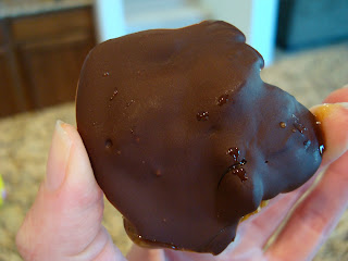 Hand holding up one Raw Vegan Chocolate Turtle showing top