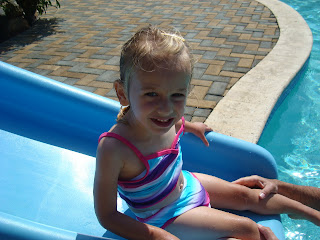 Young girl sliding down slide into pool