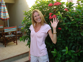 Woman in front of flowering bush waving