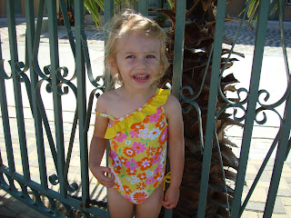 Little girl in swimsuit standing next to fence