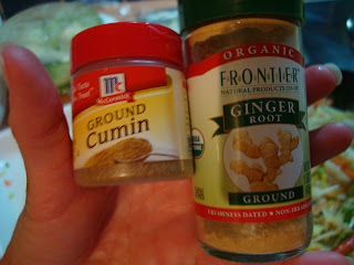 Hand holding ground cumin and ginger containers