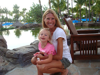 Woman and young girl hugging at hotel in front of water feature