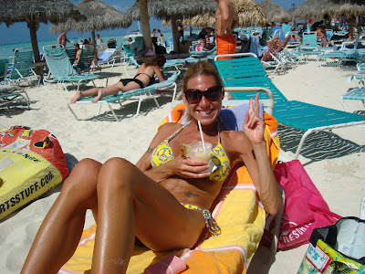 Woman laying on lounger in swimsuit holding drink