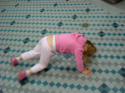 Young girl on floor on knees trying to do yoga pose