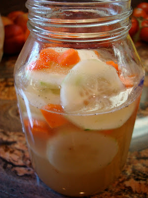 Side view of cucumbers and carrots in liquid