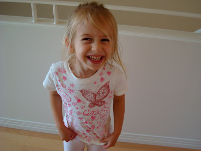 Young girl tugging on shirt and giving a huge smile