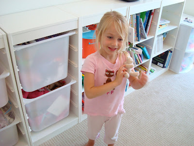 Young girl standing in room holding a toy
